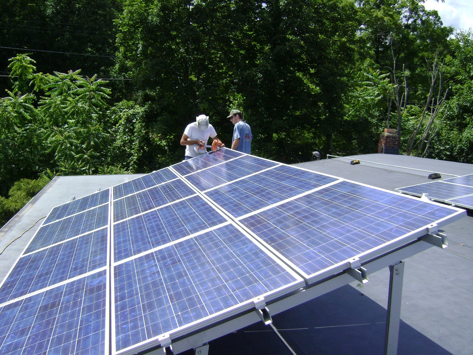 Installateurs posant des panneaux photovoltaïques sur une toiture pour un projet solaire résidentiel.